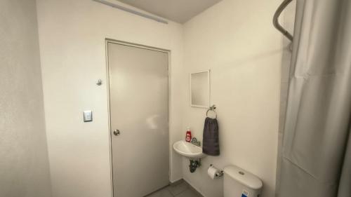 a white bathroom with a toilet and a sink at Santafe Minisuites in Hermosillo