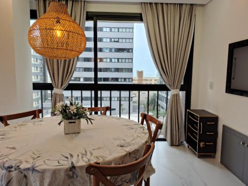 een eetkamer met een tafel en een groot raam bij Sinta se em casa, mas, com sol e mar in Torres