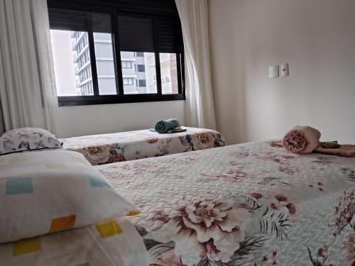 een slaapkamer met een bed met een bloemenpatroon bij Sinta se em casa, mas, com sol e mar in Torres