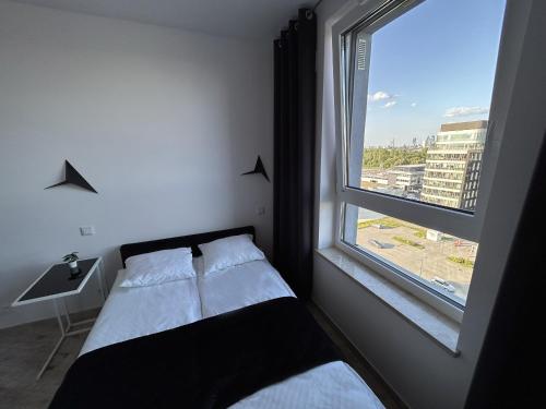 une petite chambre avec un lit et une fenêtre dans l'établissement Stay Apartment, à Varsovie