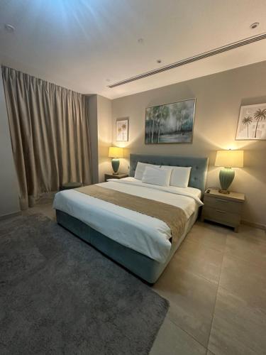 Ein Schlafzimmer mit einem großen Bett, zwei Nachttischen und zwei Lampen in der Unterkunft Magic waves holiday in Dubai