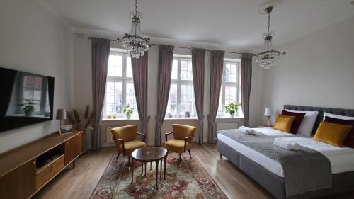 Olives Marina Apartment Old Town Gdańsk في غدانسك: غرفة نوم بسرير وكراسي وتلفزيون