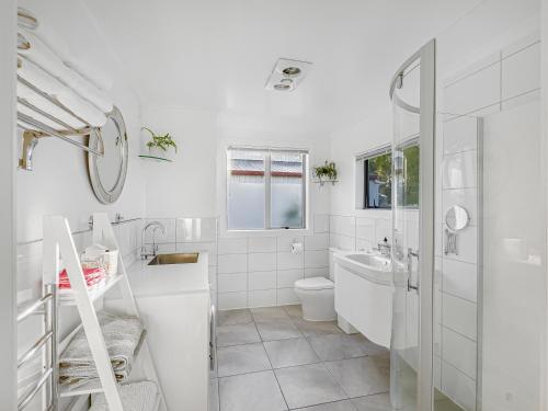 een witte badkamer met een toilet en een wastafel bij Cosy Guesthouse in Tranquil Puriri, Thames in Thames