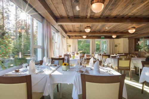 a restaurant with white tables and chairs and windows at Sunstar Hotel Arosa in Arosa