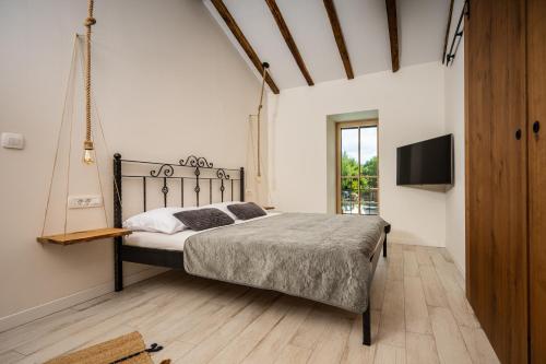 a bedroom with a bed and a flat screen tv at Villa Nika - Rustic Stone House with Heated Pool in Rasopasno