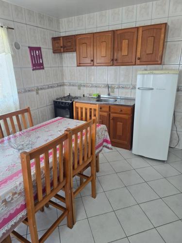 een keuken met een tafel en een witte koelkast bij Férias em Itapema 04 in Itapema
