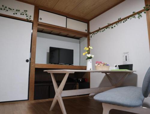 a room with a table and a tv and a door at Green House 大阪 in Osaka