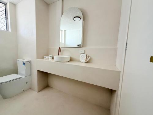 a white bathroom with a sink and a mirror at 706TheSands Beachfront Apartment at the centre of Surfers Paradise in Gold Coast
