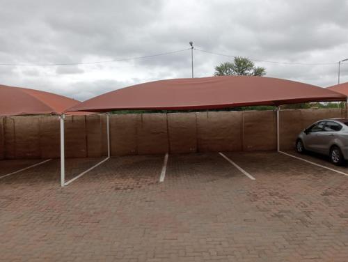 twee grote rode paraplu's op een parkeerplaats bij Fairway Gardens in Pretoria