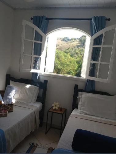 een slaapkamer met 2 bedden en een open raam bij pousada talho da serra tempera in Valença