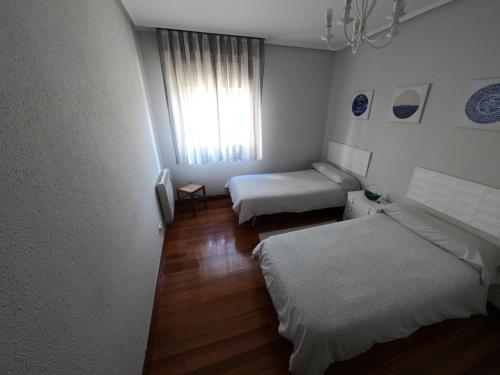 een kamer met twee bedden en een raam bij HABITACION DE DOS CAMAs BEC in Barakaldo