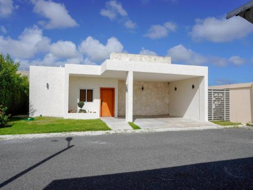 een wit huis met een oranje deur in een straat bij Villa Koi Oasis Punta Cana in Punta Cana
