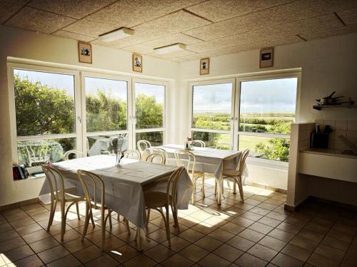 Un comedor con mesa y sillas y ventanas. en Bovbjerg Camping, en Lemvig
