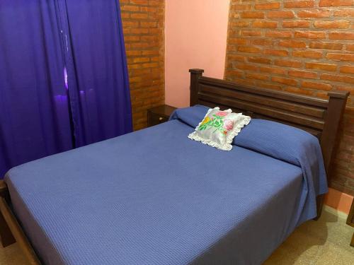- une chambre avec un lit bleu et des rideaux violets dans l'établissement Lucero de Brochero, à Villa Cura Brochero