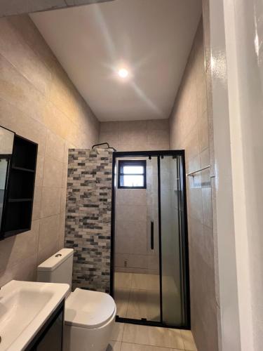een badkamer met toilet en glazen douche bij DjossayaHomes in North Legon