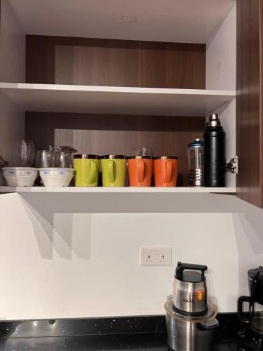 a row of colorful cups sitting on a shelf in a kitchen at DjossayaHomes in North Legon