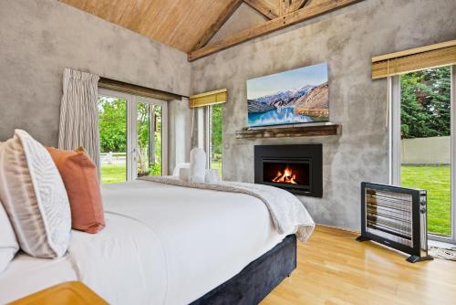 a bedroom with a bed and a fireplace at Stone Cottage in Arrowtown