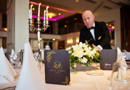 a man in a tuxedo is sitting at a table with a tablestration at Royal Marine Hotel in Dun Laoghaire
