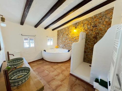 a bathroom with a tub and a stone wall at La Casa del Pastor 1890 in Benaocaz