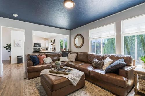 a living room with a brown leather couch and windows at Caldwell Lux Getaway! Large Family Friendly Home in Caldwell