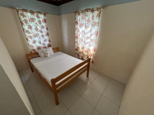 a small bedroom with a bed and curtains at C's Sunrise Escape in Roseau