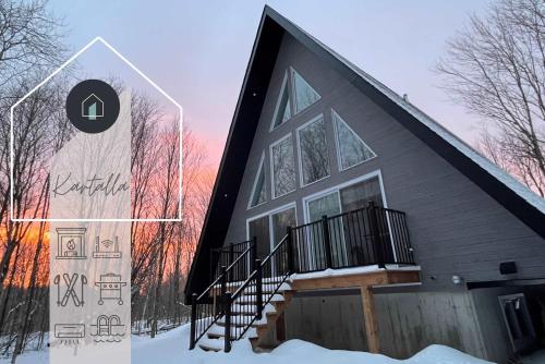 a house in the snow with a sign next to it at Kartalla - the A frame experience in Tremblant in Saint-Rémi-dʼAmherst