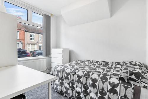 een slaapkamer met een zwart-wit bed en een raam bij OA Housing - Spacious 2 Bedrooms in Spon End