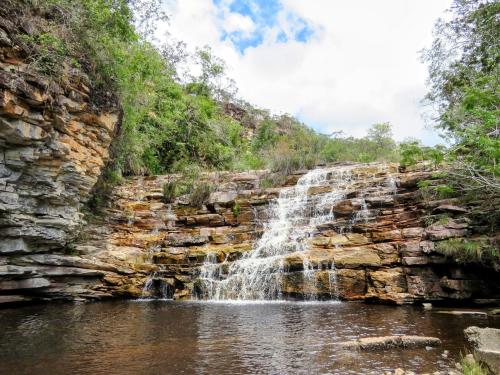una cascata sul lato di una parete di roccia di Chalé Família Canto da Graúna a Ibicoara