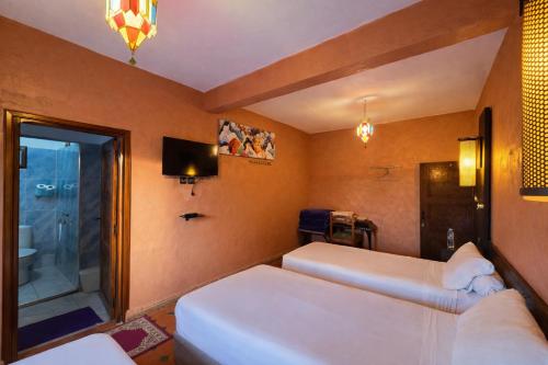 ein Hotelzimmer mit zwei Betten und einem Fernseher in der Unterkunft Gite Souss in Oulad Teïma