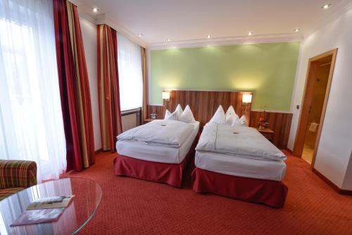 a hotel room with two beds and a glass table at Hotel Coellner Hof in Cologne