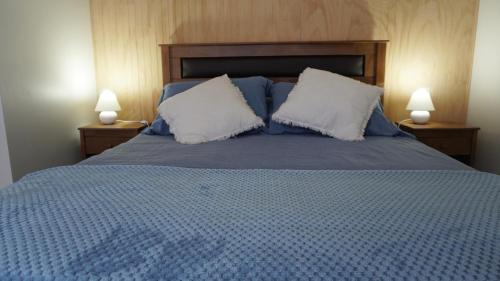 a bedroom with a blue bed with two pillows at Lodge Perry Barnes in Puerto Varas