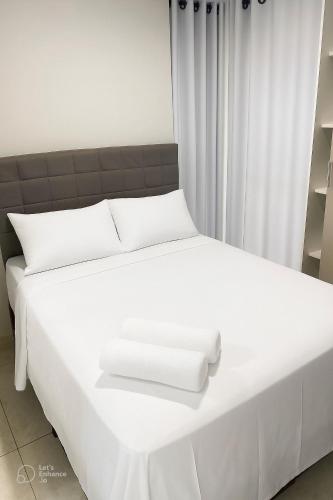 a white bed with two white towels on it at Apto elegante no Catolé 46 in Campina Grande