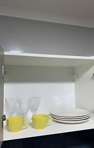 two cups and plates on a shelf in a kitchen at Apto elegante no Catolé 63 in Campina Grande