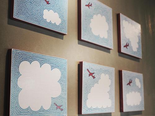 a wall with framed pictures of clouds and birds at Calendar Hotel in Otsu
