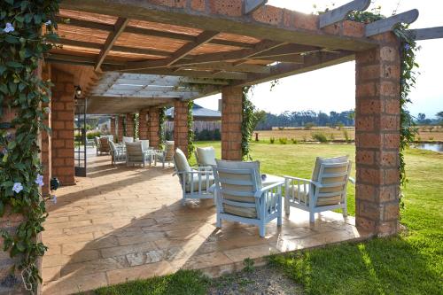 a patio with white chairs under a wooden pergola at Soames Hotel & Jack' s Bar in Nanyuki