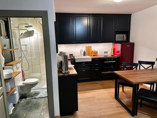 une cuisine avec des placards noirs, une table et une salle de bains dans l'établissement Travelers Studio, à Njarðvík