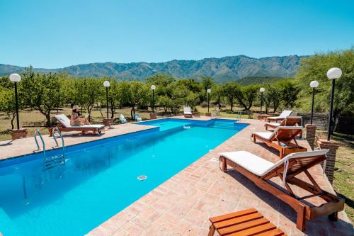 einen Pool mit Liegestühlen und einem Berg in der Unterkunft Kinien Suites de Montaña in Las Calles