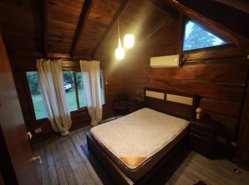 una camera da letto con un letto in una cabina di legno di Cabañas Yacoana a Valle Hermoso