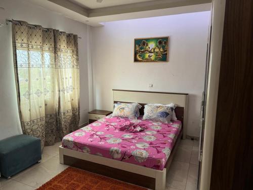 ein Schlafzimmer mit einem Bett mit einer rosa Tagesdecke in der Unterkunft Appartement 1 chambre a Bacongo in Brazzaville