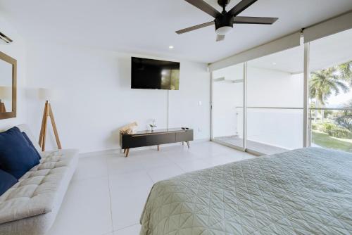 a bedroom with a bed and a tv and a couch at Departamento moderno frente a playa Nuevo Vallarta in Nuevo Vallarta