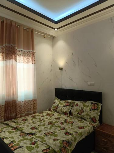 una camera da letto con un letto con un piumone e una finestra di Appartement Case de Gaule a Brazzaville