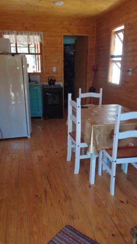 a kitchen with a table and chairs and a refrigerator at Cabaña Las Abuelas in Xuí