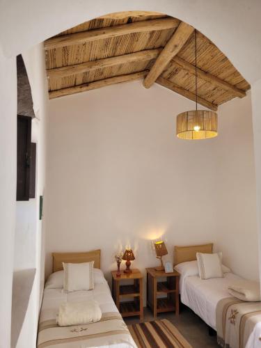 two beds in a room with wooden ceilings at La Vieja Esquina in Cachí