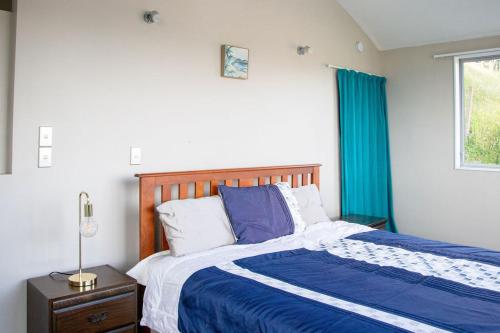 a bedroom with a bed with a blue comforter and a window at Comfort in Khandallah in Wellington
