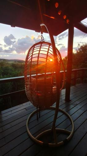 a bird cage on a porch with the sunset in the background at Cabaña Los Pololos in Villa Serrana