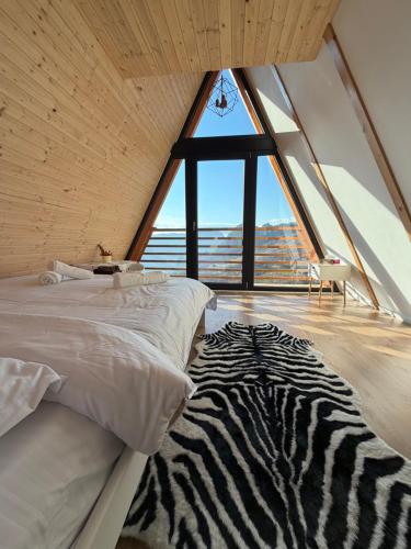 two beds in a room with a large window at Catunu lupului village Cabana Monte Benito in Cotorăşti