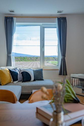 a living room with a couch and a large window at Clematis in Nakafurano