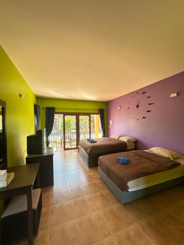 Lanta Bee Garden Bungalow SHA Extra Plus في كو لانتا: غرفة بسريرين وتلفزيون وغرفة بسريرين