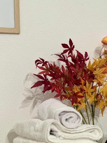 a vase of flowers sitting next to a towel at Apartment DUNJA 2 Laktasi in Laktaši