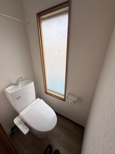a white toilet in a bathroom with a window at りんくう館笠松 関西空港 in Sano